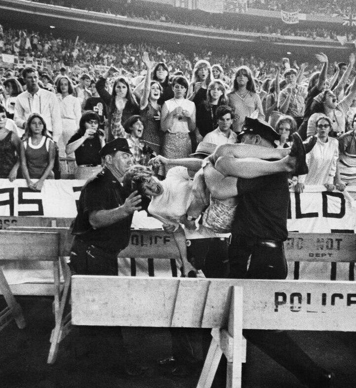 Полицейские пытаются угомонить молодую фанатку во время концерта Beatles в Нью-Йорке, 23 августа 1966 года. 