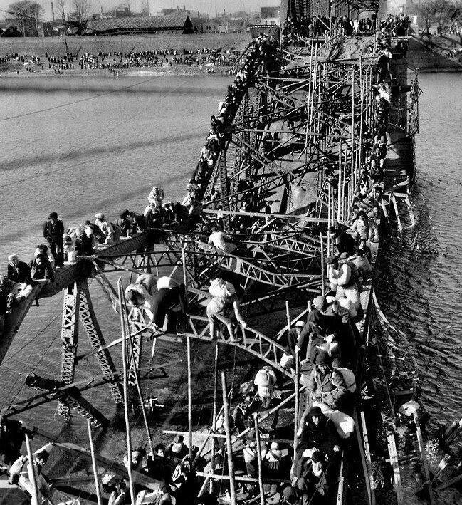 Жители Пхеньяна спасаются бегством из осажденного города по опорам разрушенного моста. Корейская Война. Октябрь 1950 г. 