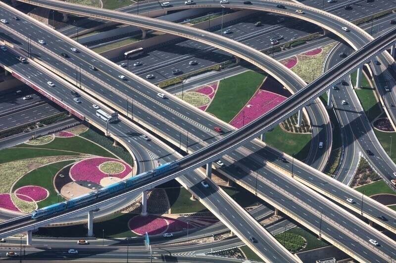 Полностью автоматизированная железнодорожная линия метро пересекает дороги и ухоженный сад в Дубае, ОАЭ, сентябрь 2019 года