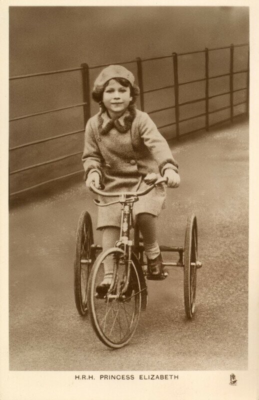 Принцесса Елизавета катается на трехколесном велосипеде в парке. 1935