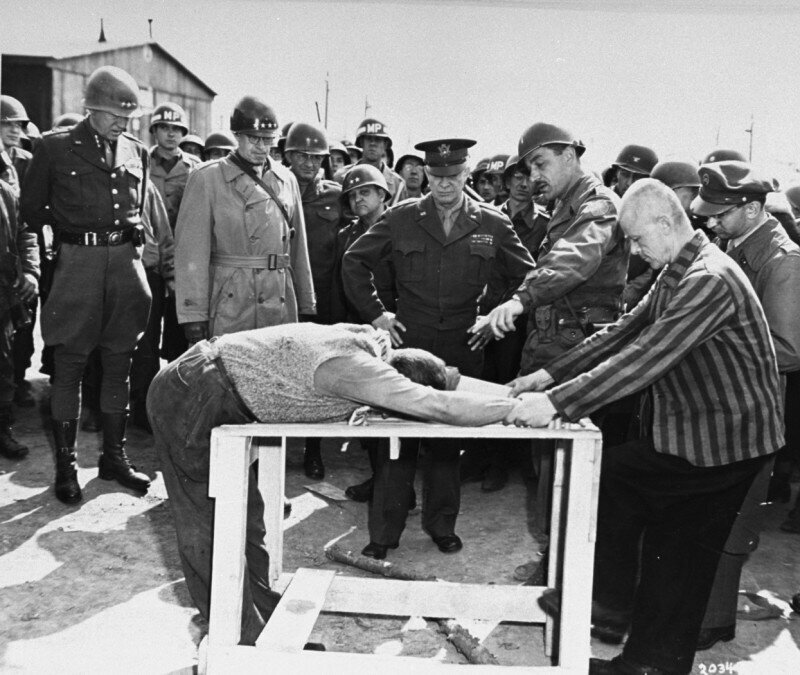 Генералы Эйзенхауэр, Брэдли и Паттон наблюдают, как бывшие узники концлагеря демонстрируют методы пыток, которым они подвергались. Ордруф, Германия. 12 апреля 1945 г.
