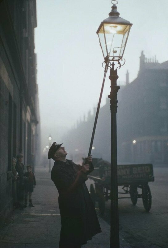 Фонарщик зажигает газовую лампу на улице в Глазго, Шотландия, 1955