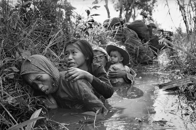17. Жители Вьетнама укрываются в грязном канале, прячась от пожара в 1966 году