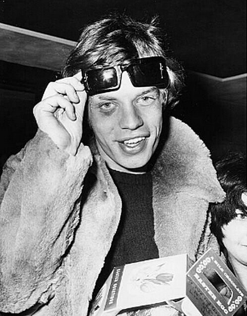 Мик Джаггер поднимает очки, чтобы показать синяк, который он получил во время тура по Франции, когда он раздавал автографы фанатам в лондонском аэропорту 6 апреля 1966 года. 