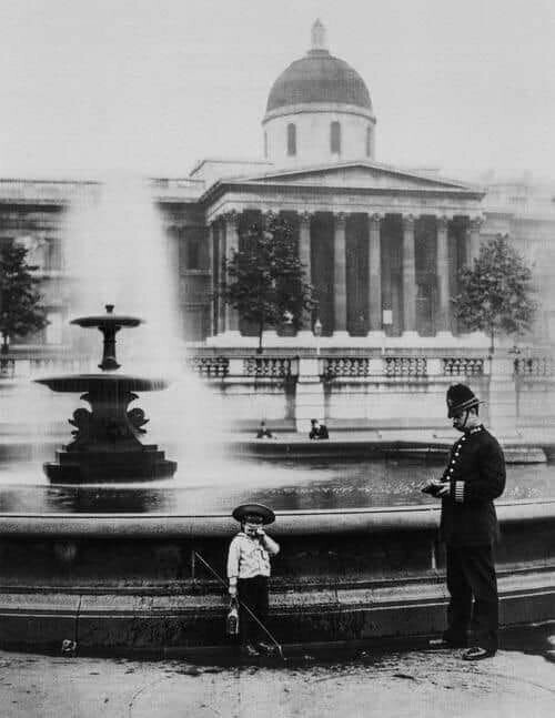 Полицейский задаёт неудобные вопросы молодому человеку, который решил порыбачить в фонтане на Трафальгарской площади в Лондоне, 1892. 