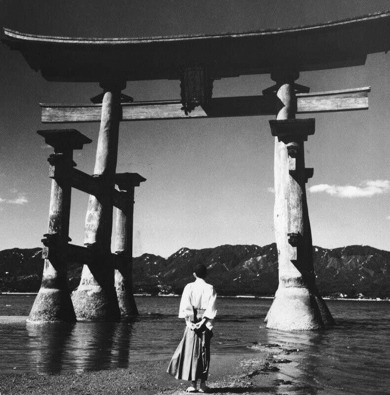 Синтоистский священник смотрит на тории святилища Ицукусима, 1955 год, Япония.