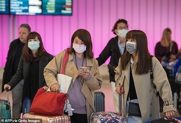 Пассажиры в защитных масках в международном аэропорту Лос-Анджелеса