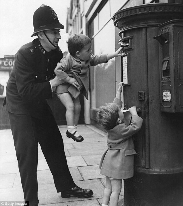 Полицейский помогает ребенку отправить письмо. Великобритания. 1950-е 