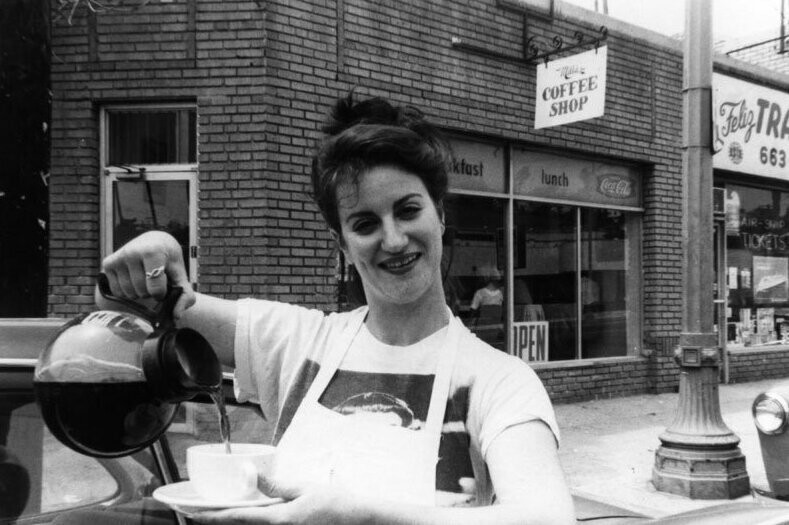 Официантка наливает кофе напротив уличного кафе