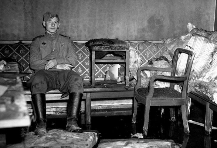 Советский солдат отдыхает в комнате, в которой Гитлер покончил с собой
