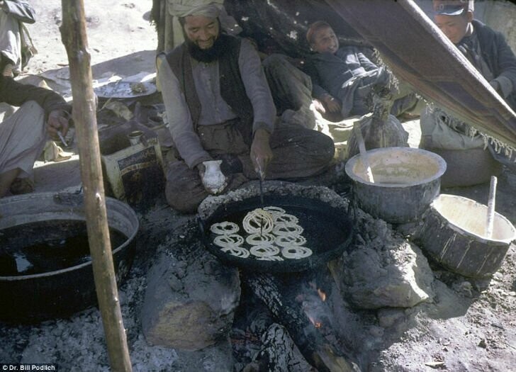 Мужчина готовит сладкий десерт джалеби на открытом огне.