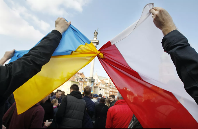 Люди держат связанные флаги Польши и Украины в Варшаве