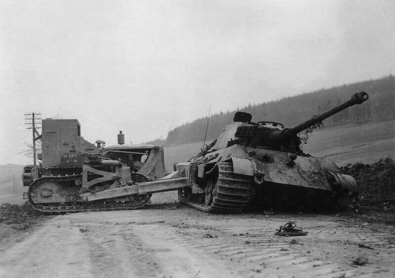 Американский бульдозер D7 из 1-го инженерного батальона 1-й армии сталкивает уничтоженный немецкий тяжёлый танк "Королевский тигр" из 507 тяжёлого танкового полка на обочину. Окрестности Остероде, Германия, 12 апреля 1945 г