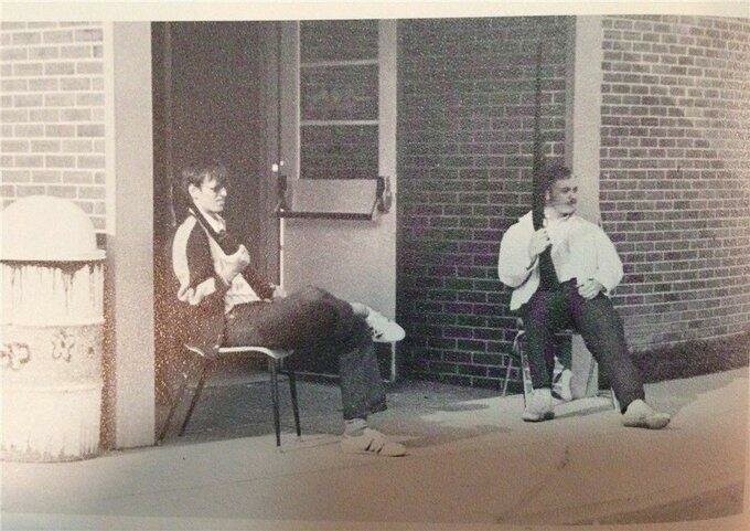 Студент и преподаватель сидят на пороге местной средней школы после анонимного звонка об угрозе масс-шутинга, Делавэр, США, 1973 год
