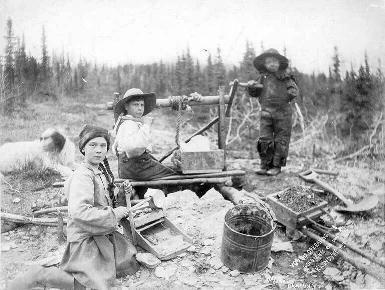Трое детей просеивают песок на золотом прииске Доминион, Юкон, Аляска