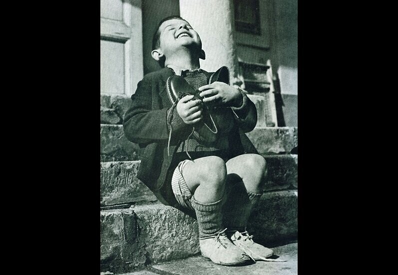 Мальчик получил в подарок ботинки. Фото сделано во время Второй Мировой войны.