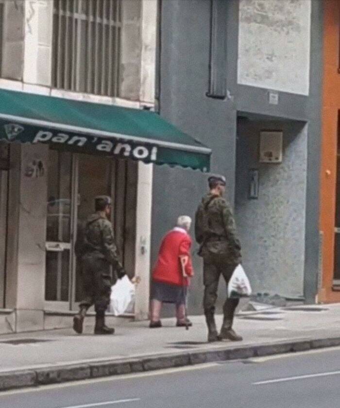 Испанские солдаты помогают пожилой женщине во время карантина