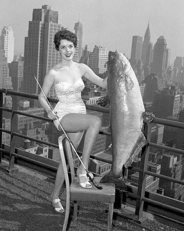 ейл Хупер, 18 лет, из Мемфиса, штат Теннесси, выбранная в качестве мисс Национальной Королевы сомов, держит 56-фунтового сома в отеле New Yorker, 1954 год
