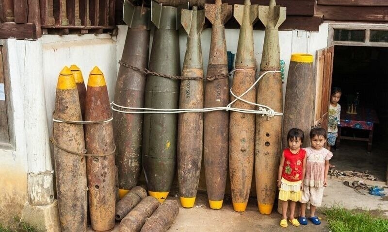 Дети позируют рядом с неразорвавшимися снарядами, найденными вокруг деревни.