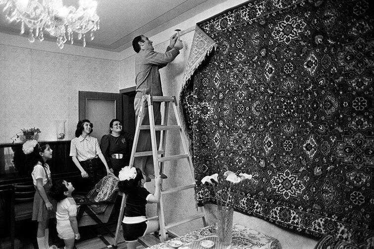 Глава семьи под восторженными взглядами своих родных прибивает к стене роскошный ковёр. СССР, 1970-е
