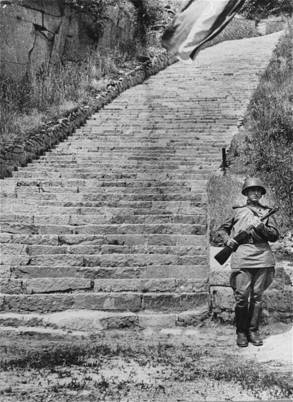 Сержант Красной Армии на посту почетного караула у «лестницы смерти» в карьере вблизи бывшего концлагеря Маутхаузен. Лето 1945 г.