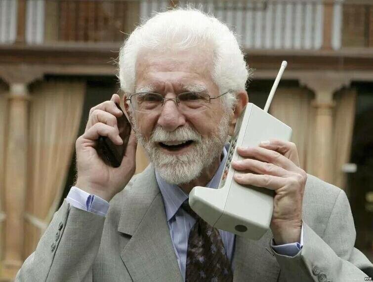 Мартин Купер, изобретатель первого мобильного телефона, позирует с современным смартфоном