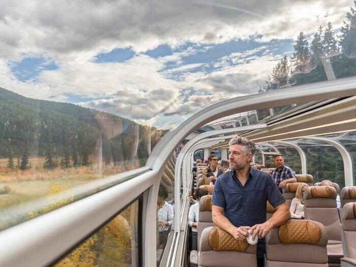 Пассажиры в классе GoldLeaf на борту Rocky Mountaineer, который путешествует по канадским Скалистым горам, могут отдохнуть в потрясающем вагоне со стеклянным потолком