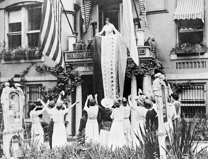 Суфражистка Элис Пол вывешивает баннер с балкона штаб-квартиры национальной женской партии. Каждая звезда относится к штату, принявшему поправку, позволяющую женщинам голосовать. 18 августа 1920 года.