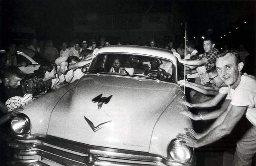 Разъяренная толпа белых граждан США пытается преградить путь и раскачать машину чернокожих, которые пытаются отъехать от первого учебного заведения для интегрированного обучения представителей разных рас в Клинтоне, штат Теннеси (1956 год)