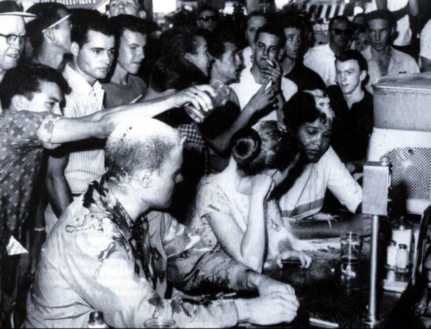 Белые посетители кафе издевательски обсыпают мукой и обливают напитками чернокожую девушку и двух ее сторонников, которые вопреки старым расистским традициям посмели усесться за стойкой (1963 год)