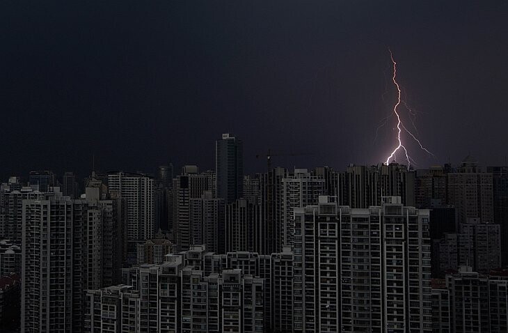 Удар молнии над темными зданиями в центре Шанхая во время шторма. (Фото Aly Song):