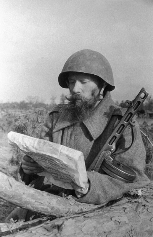 Красноармеец Гаврила Лебедев читает газету на передовой. 1944