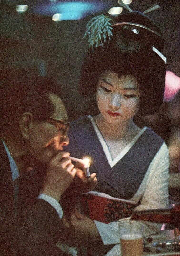Гейша даёт прикурить мужчине в одном из баров Токио, Япония, 1969 год