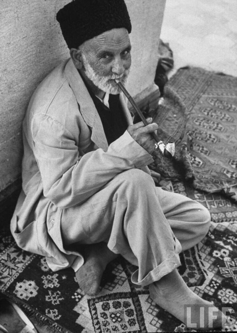 Старый мусульманин наслаждается курением перед входом в мечеть