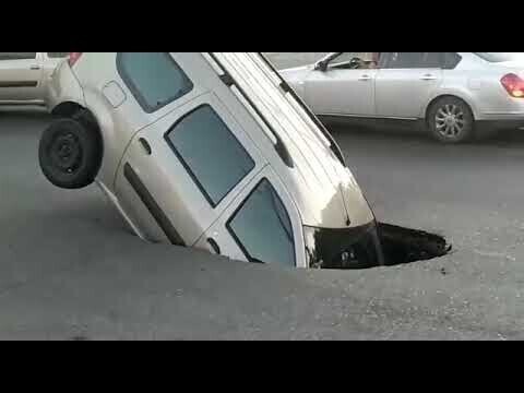 Провал на дороге наполовину поглотил автомобиль в Астрахани 