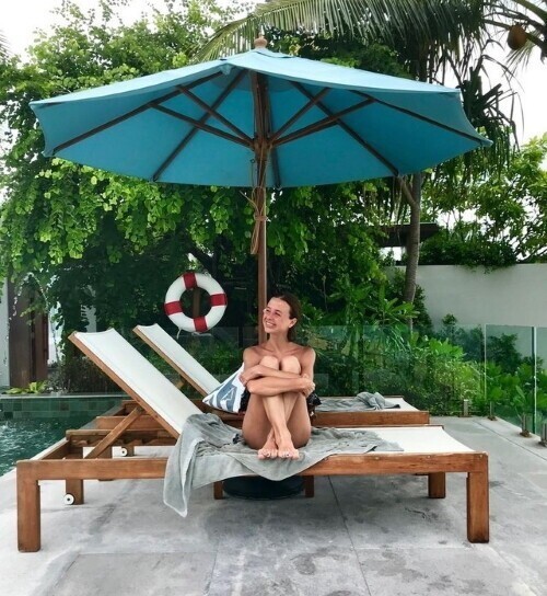 Фото из Таиланда, где она сидит на шезлонге у бассейна или на балконе