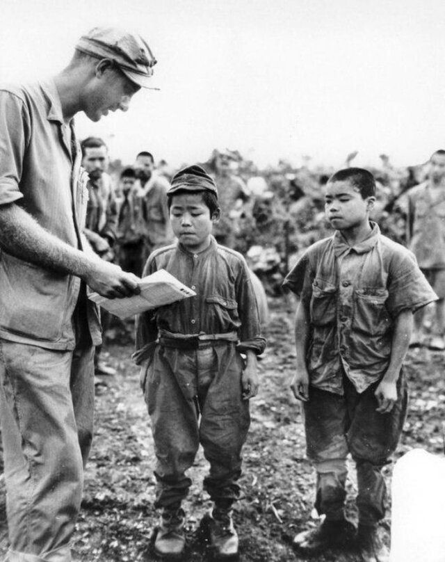 Первый лейтенант морской пехоты Харт Шпигал пытается что–то объяснить пленным японским солдатам. 1945 год, Окинава, Япония