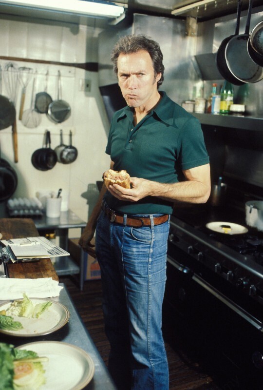 Клинт Иствуд ест гамбургер на кухне своего ресторана «Hog's Breath Inn» в Кармел, Калифорния. Конец 1970-х гг.