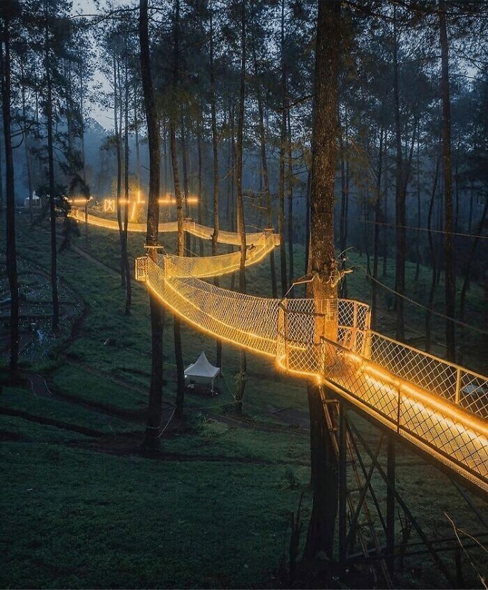 Это деревянный подвесной мост, полностью освещенный теплым желтым светом