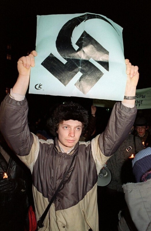 Армянский демонстрант держит советскую эмблему с молотом и серпом в виде нацистской свастики в Москве во время акции протеста против объявления Кремлем чрезвычайного положения в Нагорном Карабахе, 15 января 1990 года.