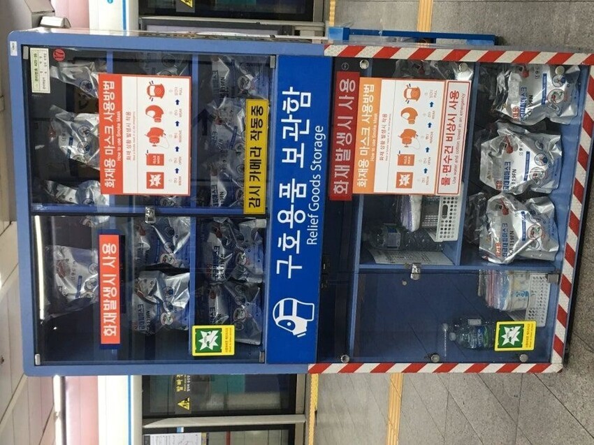 Станции с товарами первой необходимости, подобные этой, можно увидеть по всей Южной Корее, даже на железнодорожных вокзалах. Они содержат: противогазы, бутилированную воду и аптечки первой помощи