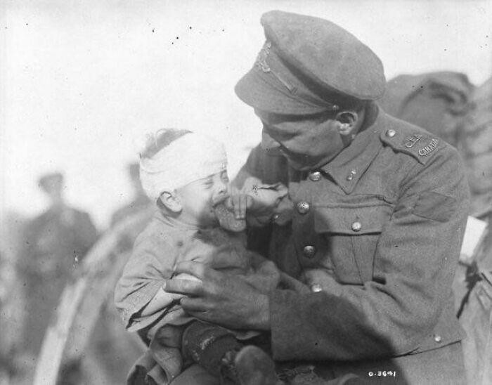 29. Первая мировая война. Канадский солдат утешает раненого бельгийского младенца, мать которого погибла от артиллерийского снаряда. Ноябрь 1918 года.