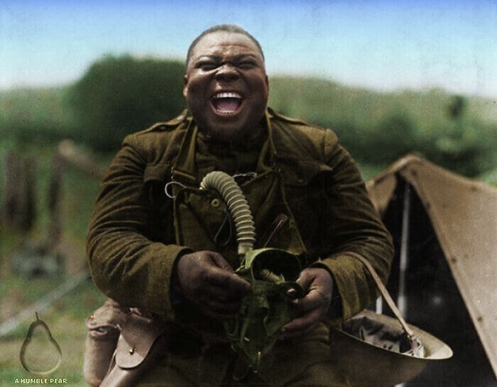 Чернокожий солдат из 3-го батальона 366-го пехотного полка США, смеющийся при виде товарищей в противогазах, 1918 г.