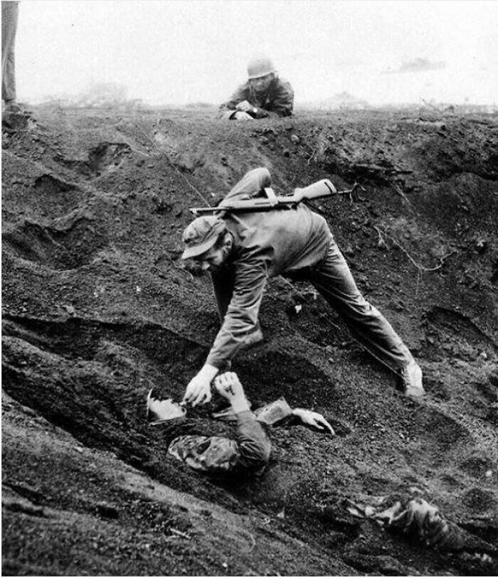 Морской пехотинец США дает сигарету японскому солдату, погребенному в песке. Иводзима, 1945 год.