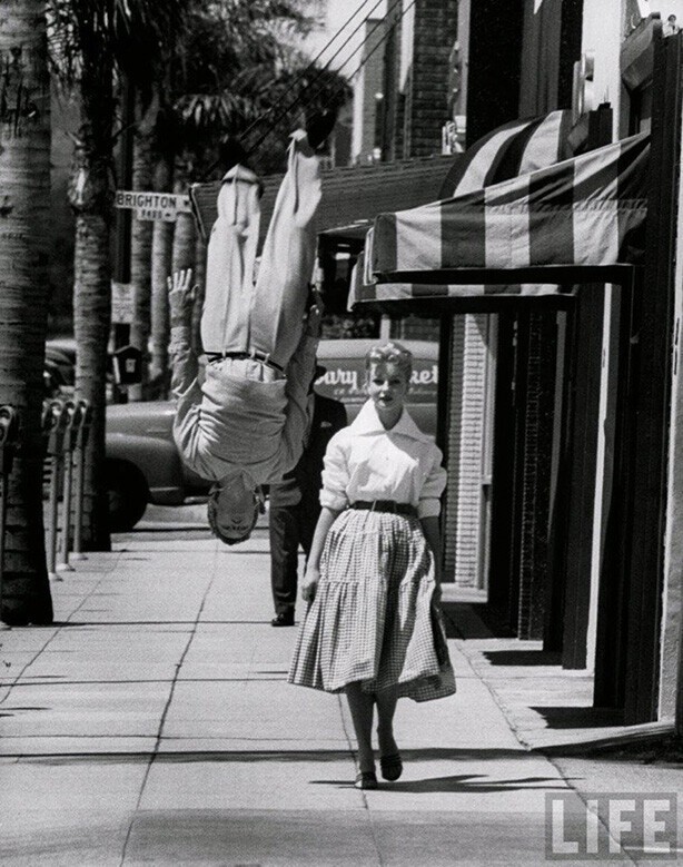 Акробат и актер Расс Тэмблин делает сальто во время прогулки с актрисой Венецией Стивенсон, 1955 г.