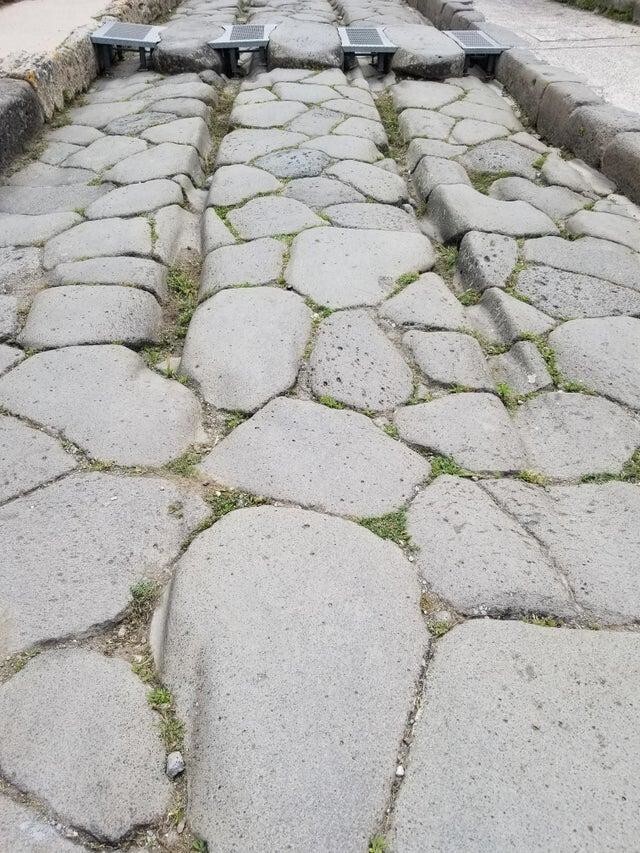 Эти следы были выбиты колесами повозок на каменной дороге в Помпеях тысячи лет назад.
