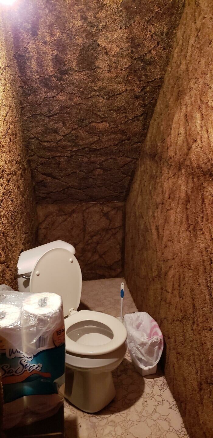 4. Туалет "под лестницей", в котором унитаз стоит по диагонали и частично встроен в стену (обитую ковролином)