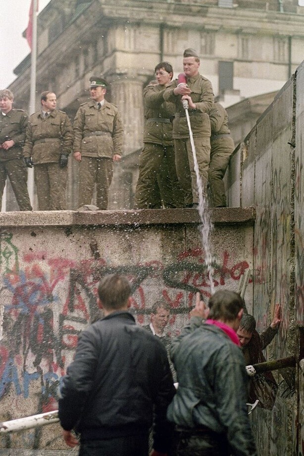 Пограничники ГДР обливают водой гражданских из ФРГ, которые рушат пограничную стену, 1989 год