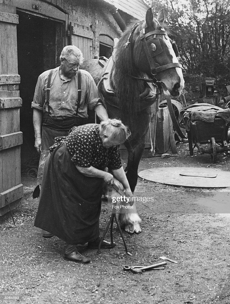 70-летняя Элизабет Арнольд, считающаяся единственной женщиной-кузнецом в Англии, подковывает лошадь возле 400-летней кузницы в Кенте, 1938