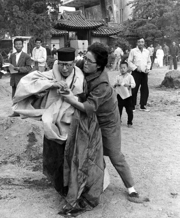 Женщина забирает спички у буддийского монаха, который облился бензином и пытается совершить самосожжение. Сеул, Южная Корея, 1963 год.